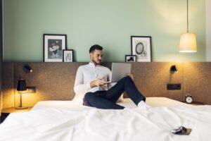 Mann mit Laptop im Bett sitzend