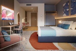 Zimmer mit Doppelbett, Schreibtisch und Sessel in Pasteltönen