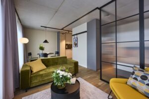 Wohnbereich mit Sofa und Sessel, andere Bereiche durch Glasschiebetüren abgetrennt