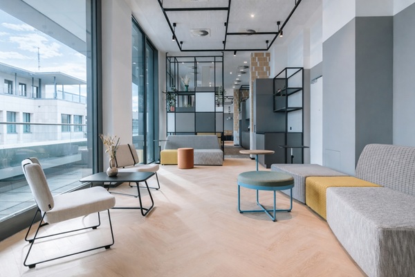 Minimalistisch möblierter Raum mit schlanken sesseln und einem Beistelltisch vor einem Regal als Raumteiler