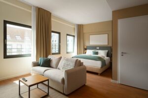 Schlafzimmer in Beige, Weiß und Petrolgrün mit Doppelbett und Sofa