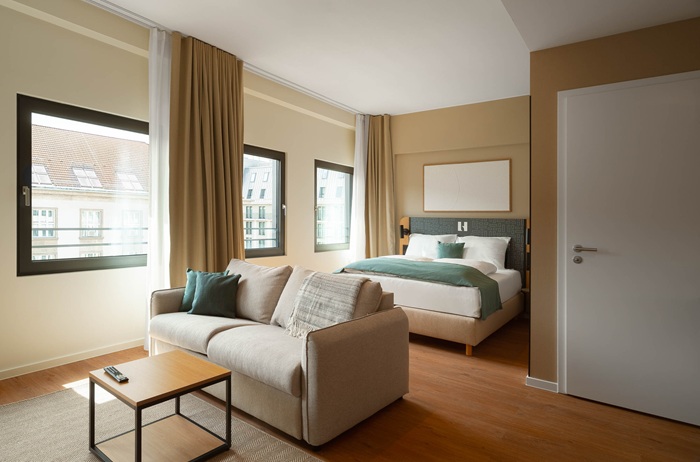Schlafzimmer in Beige, Weiß und Petrolgrün mit Doppelbett und Sofa
