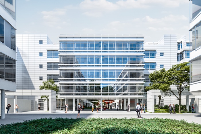 Modern glass-front office building with a central glass atrium, people walking along a courtyard lined with trees and greenery.